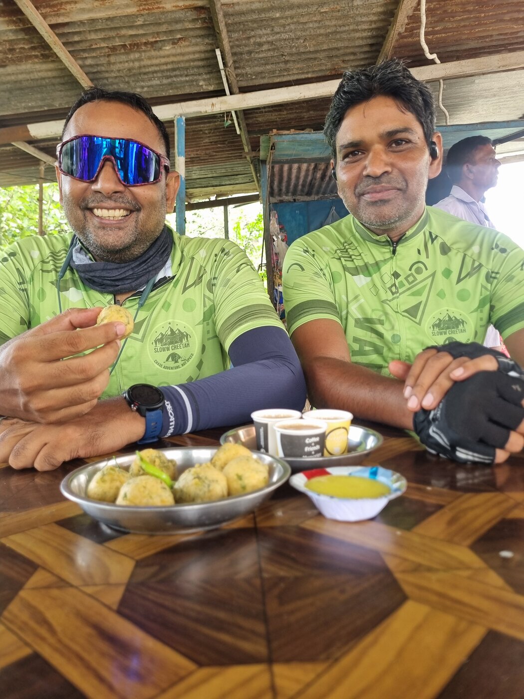 Cyclist in the Vadodara heritage jersey at a roadside vada-pav and chai stop